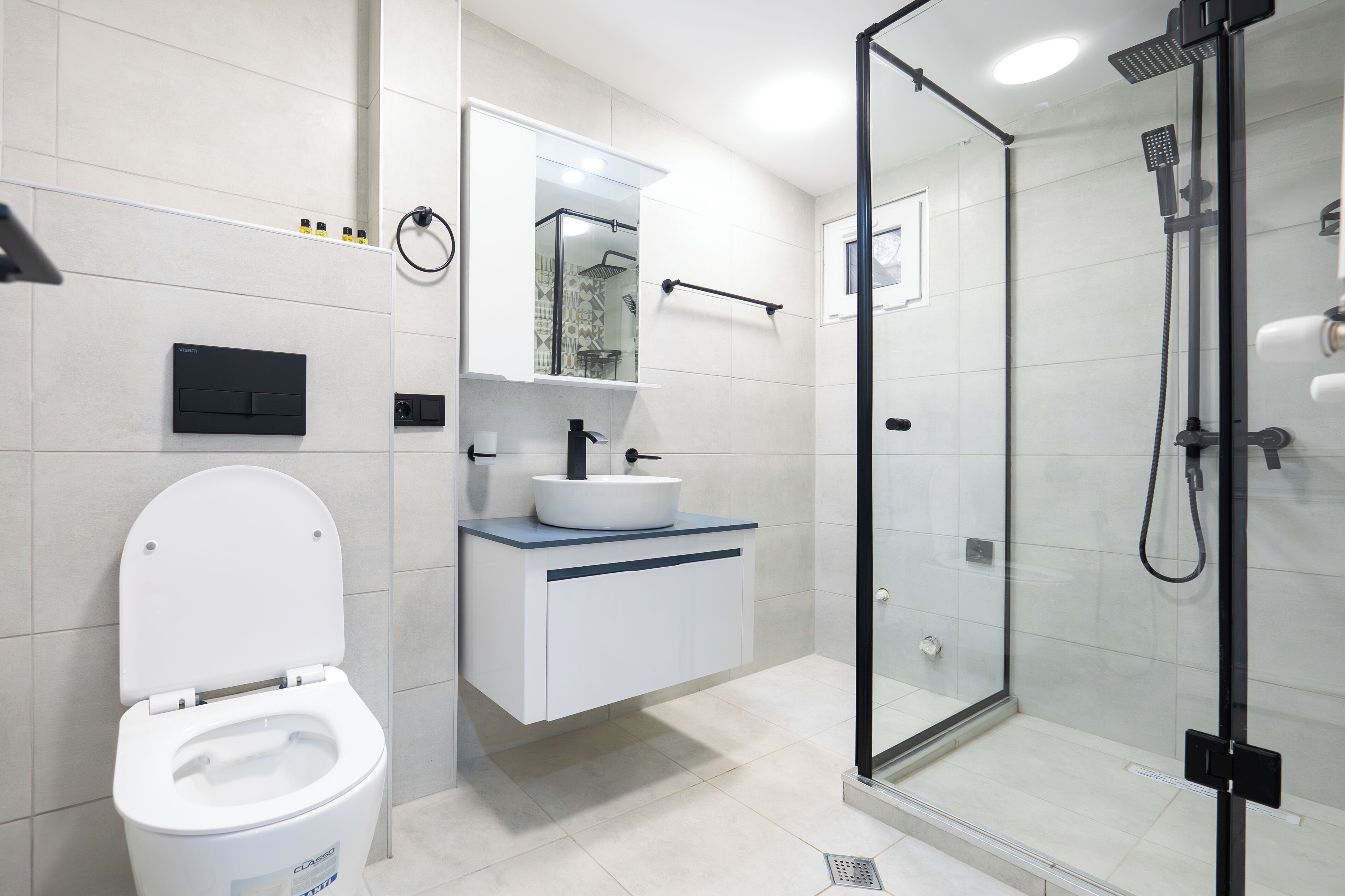 A modern bathroom with a toilet, sink, and glass-enclosed shower.