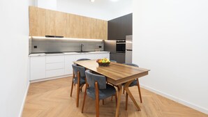 A modern kitchen with wooden cabinets, a built-in stove, and a dining area with a wooden table and chairs. - Chic & Modern 4BR Home in Old Tbilisi (Tbilisi)