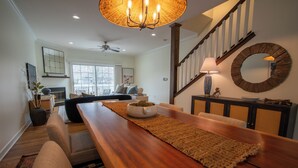 A spacious living room with a wooden dining table, a sofa, and a staircase. - Downtown Saugatuck Dream (Saugatuck)