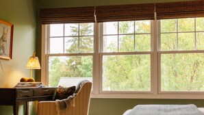A room with a large window, a desk with a lamp, and a chair with a blanket. - Downtown Saugatuck Dream (Saugatuck)