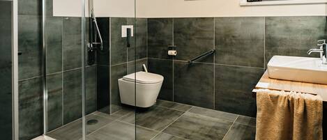 A modern bathroom with a glass shower enclosure, a toilet, and a sink with a towel.