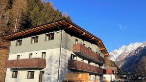 A multi-story building with a wooden balcony, set against a mountainous backdrop. - Nature House (Brennero)