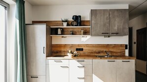 A modern kitchen with white cabinets, a wooden countertop, and a built-in coffee maker. - Nature House (Brennero)