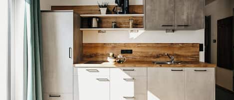 Una cucina moderna con mobili bianchi, un piano di lavoro in legno e una macchina da caffè integrata.