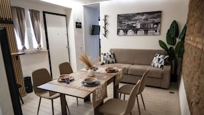 A dining area with a table set for four, a sofa, and a television in the background. - Maison Monteverde/ Trastevere (Roma)
