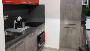A modern kitchen with red and grey cabinetry, a black countertop, and a stainless steel sink. - Maison Monteverde/ Trastevere (Roma)