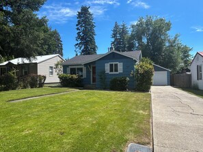 A residential house with a front lawn, a garage, and a driveway. - Cozy 2BR near Lake Coeur d'Alene w/ updated kitchen & deck (Coeur d'Alene)