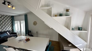 Ein modernes Wohnzimmer mit weißer Wendeltreppe, einem Esstisch und einem Sofa.