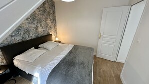 Ein Schlafzimmer mit einem Bett, einem Nachttisch, einer Lampe, einer Tür und einer strukturierten Wand.