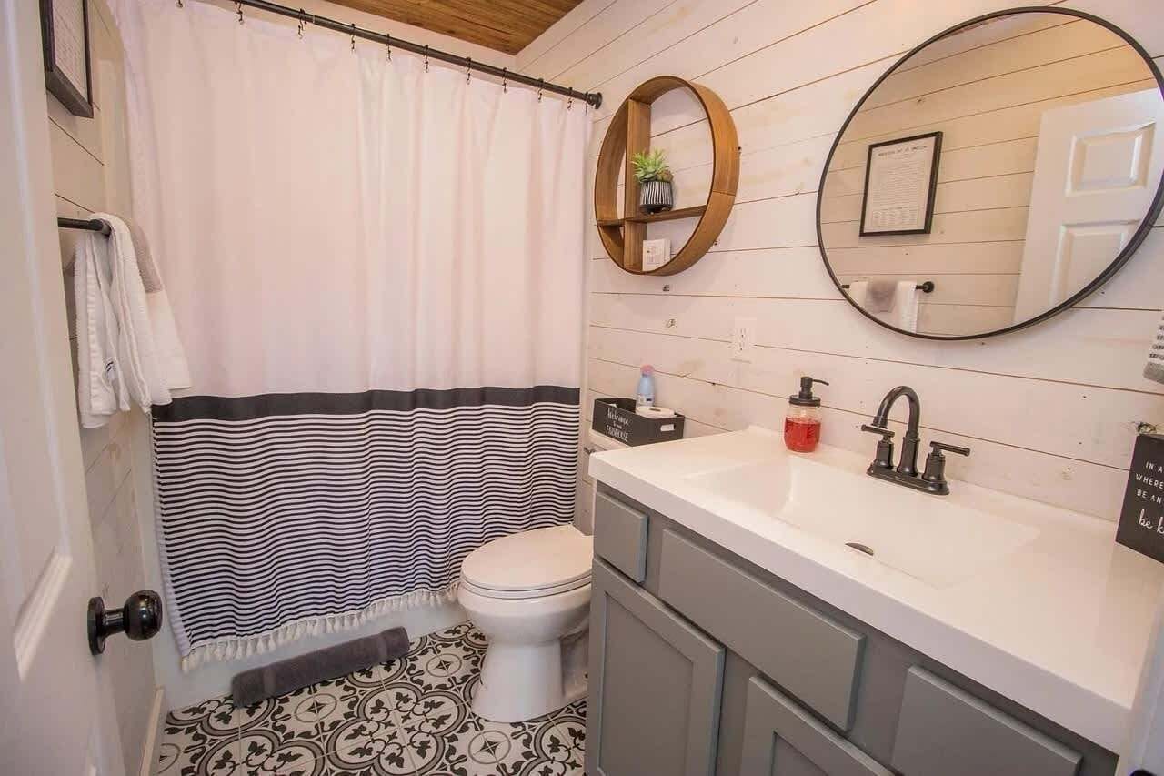 Ein Badezimmer mit Toilette, Waschbecken, Spiegel und Duschvorhang.