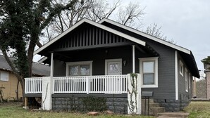 Une maison de plain-pied avec un porche à l’avant, un petit jardin devant et une boîte aux lettres bien visible.