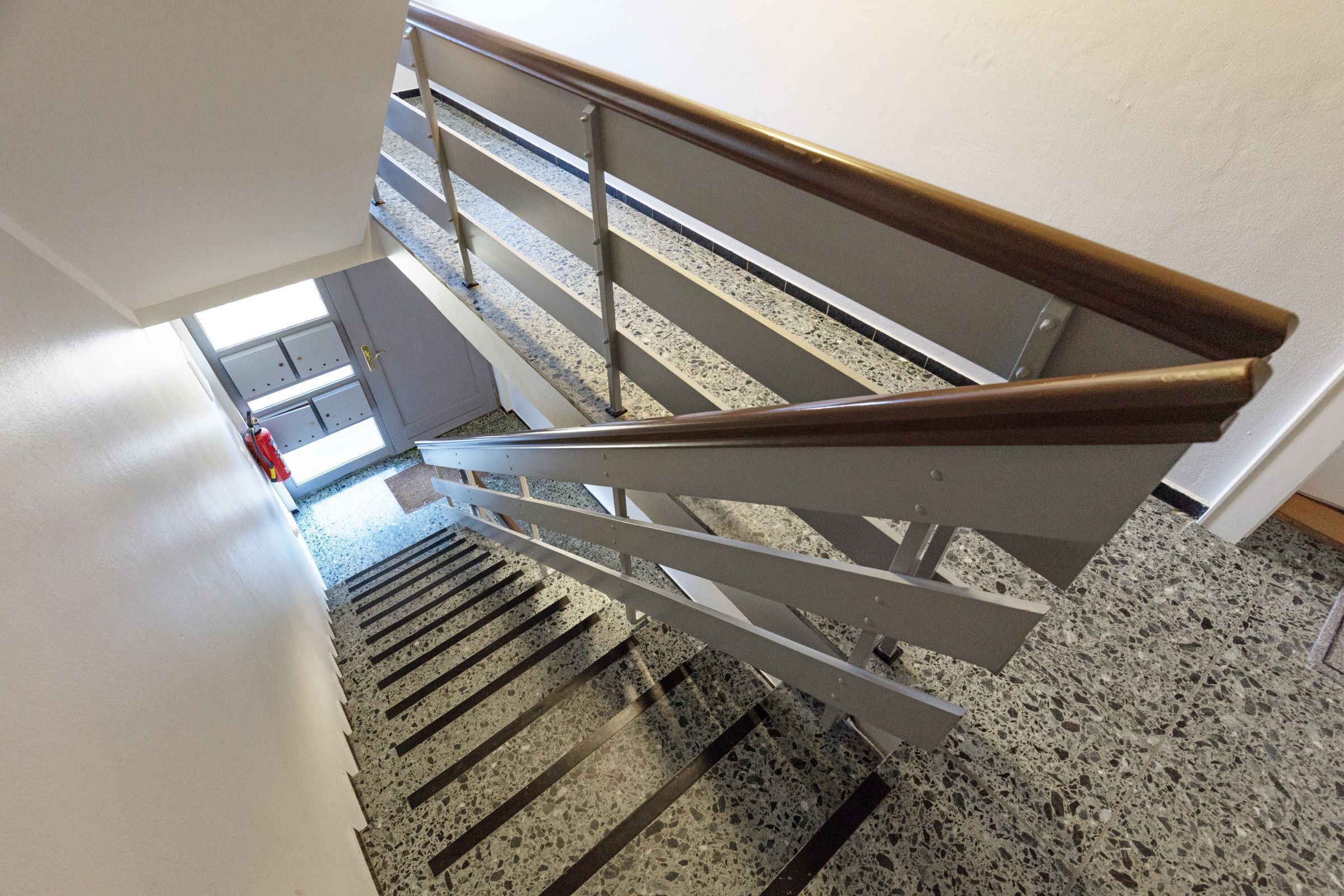 Una escalera con barandilla de metal y suelo de terrazo.