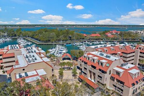 Un port de plaisance où sont amarrés des bateaux, entouré de bâtiments aux toits rouges et offrant une vue sur un lac.