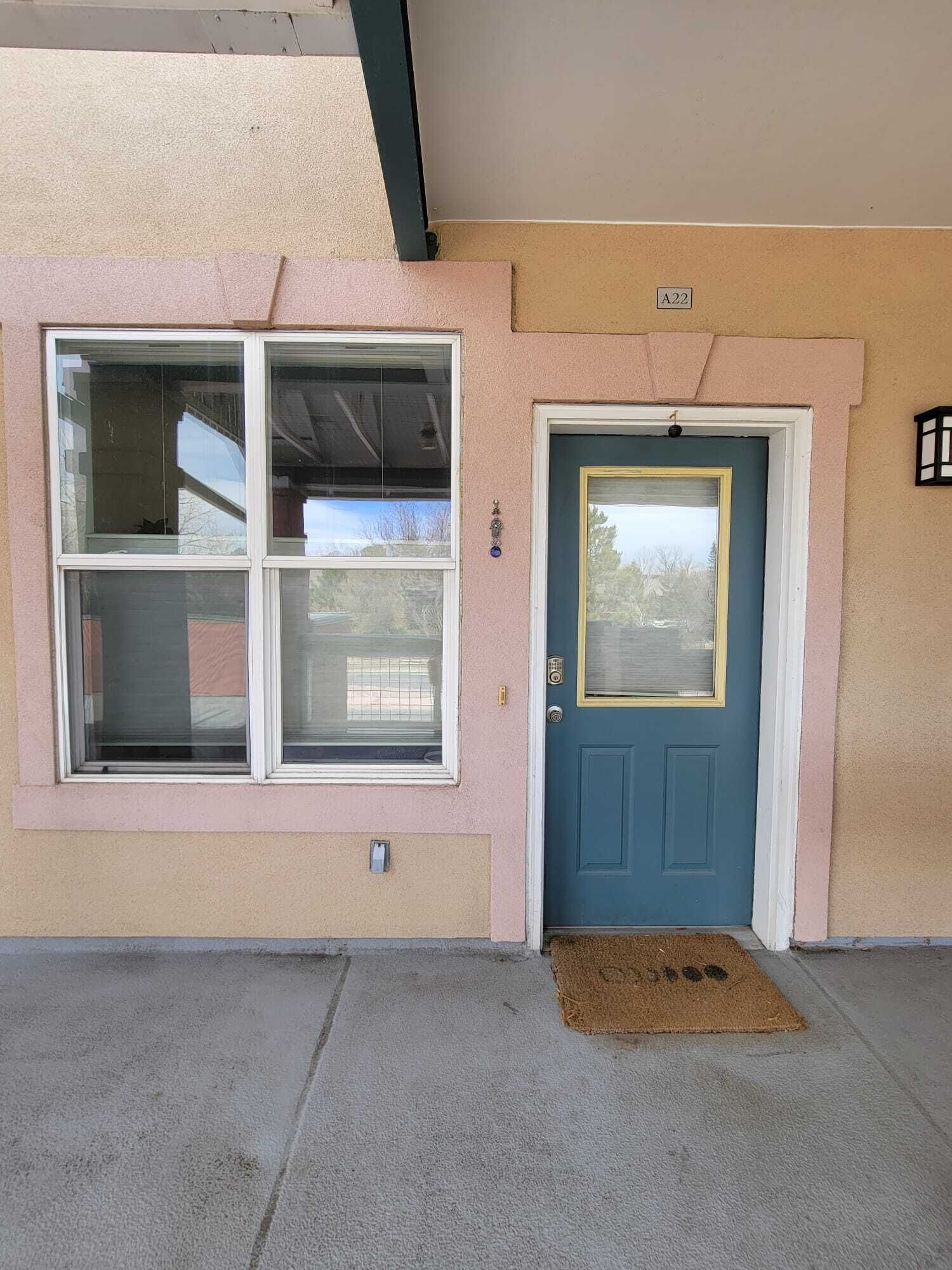 A building with a blue door, a window with a white frame, and a small sign above the door.