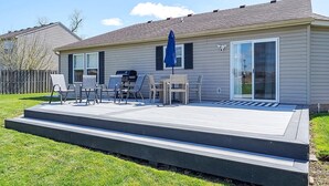 A residential deck with outdoor furniture and a blue umbrella. - The Cozy Charcoal Cottage | Garage | Grill & Patio (Brownsburg)