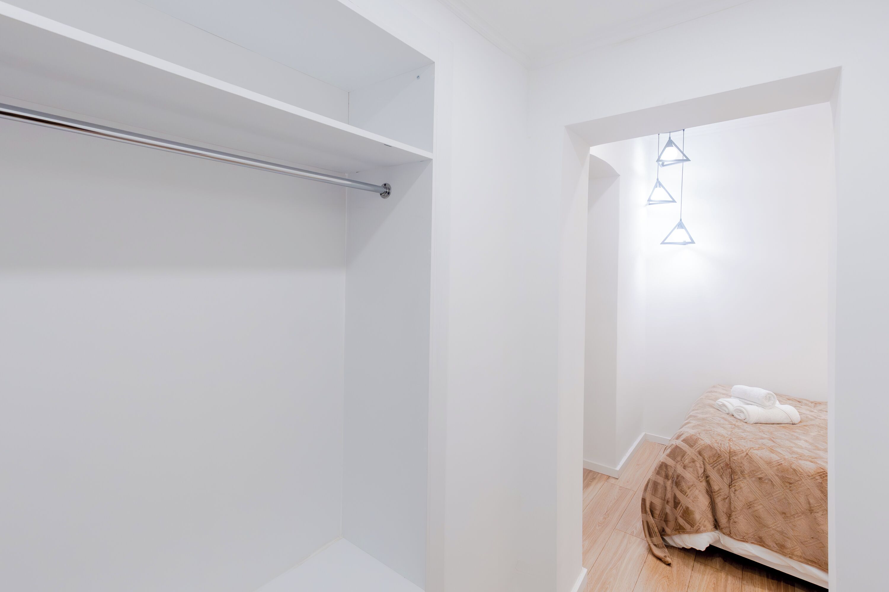 Un dormitorio minimalista con una cama, una lámpara colgante y un armario empotrado.