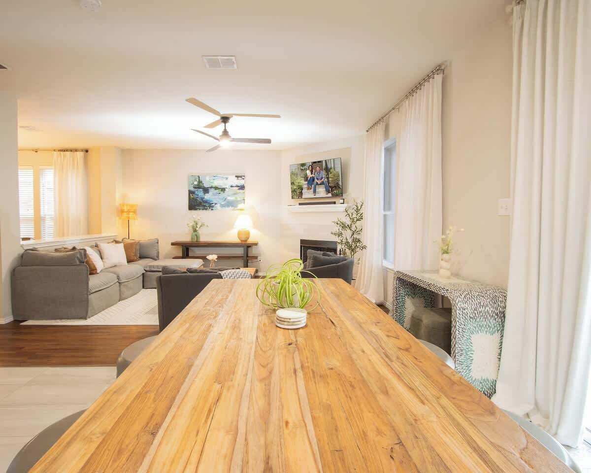 Amplia sala de estar con una mesa de comedor de madera, un conjunto de sofá, una chimenea y un ventilador de techo.