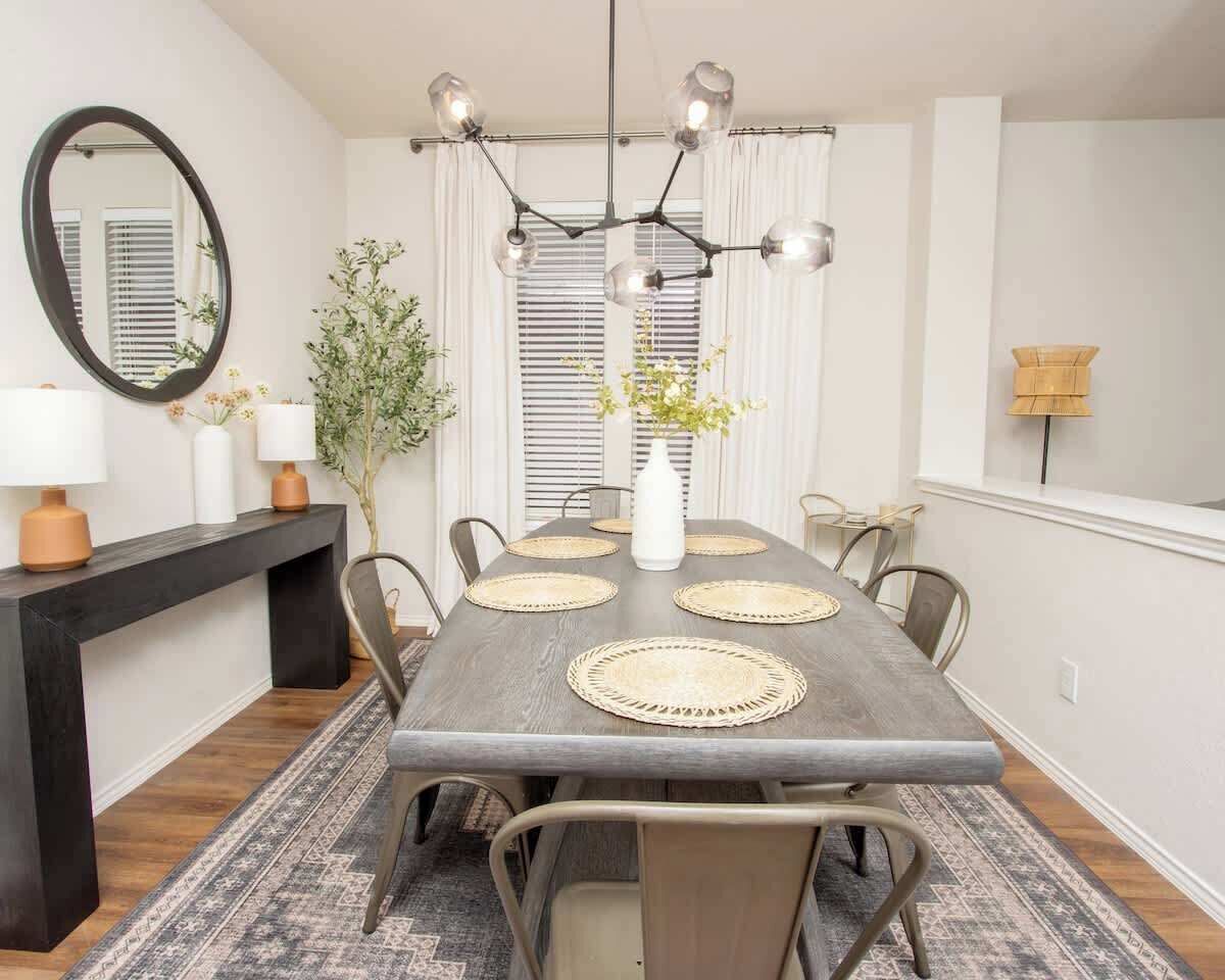 Un comedor con una mesa larga, individuales tejidos y una lámpara moderna.
