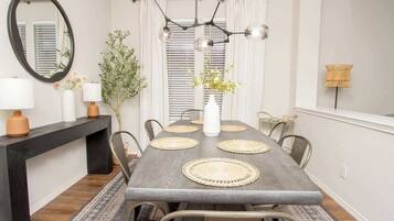Un comedor con una mesa larga, individuales tejidos y una lámpara moderna.