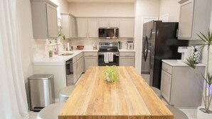 Une cuisine moderne avec une table à manger en bois, des appareils en acier inoxydable et des meubles de couleur claire.