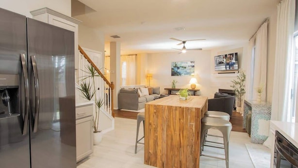 Une cuisine moderne dotée d’un îlot central, d’appareils électroménagers en acier inoxydable et d’un escalier menant à un autre niveau.