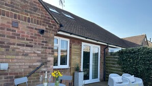 A patio with a table and chairs, a potted plant, and a white outdoor sofa. - Stylish, Contemporary Home in Earl Shilton (Leicester)