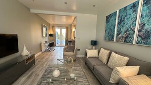A modern living room with a sofa, a coffee table, a TV, and artwork on the wall. - Stylish, Contemporary Home in Earl Shilton (Leicester)