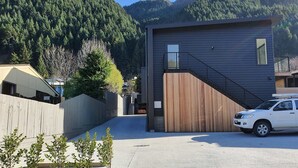 Un edificio moderno con fachada de madera, una escalera y un coche estacionado al frente.