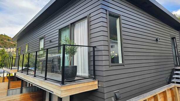 Una casa moderna con antena parabólica, ventanas amplias y un balcón con una planta en maceta.