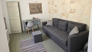 A compact living space with a grey sofa, a small desk, and a map on the wall.
