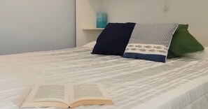 Un lit avec une couvre-lit à motifs, des oreillers et un livre ouvert posé sur le lit.