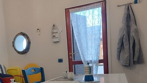 Un comedor con una mesa blanca, sillas y una ventana con cortina.