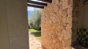 Une salle de bain avec un mur en pierre, un sol carrelé et une douche.