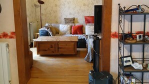 Una sala de estar acogedora con techo de madera, papel tapiz estampado, un sofá con cojines, una mesa de centro y una estantería.