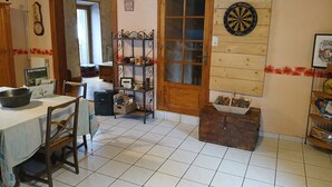 Una habitación acogedora con una mesa de madera, sillas, un dardo y un estante con diversos objetos.
