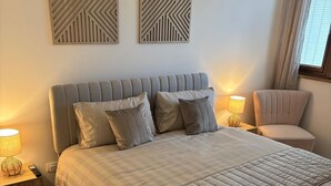 A bedroom with a large bed, two nightstands, a chair, and decorative wall art. - Bungalow 15 in Villereal Rives Southwest France (Rives)