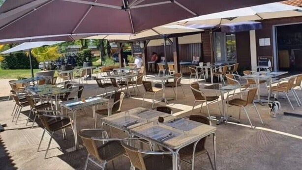 An outdoor café with multiple tables and chairs, shaded by large umbrellas. - Bungalow 15 in Villereal Rives Southwest France (Rives)