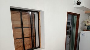 A dining area with a wooden table and chairs, a window with blinds, a small cabinet with a bird decoration, and a welcome sign. - Detached 50 m2 apartment in village house. (CAROMB)