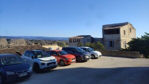 A parking area with several cars parked in front of a building with a stone facade. - Detached 50 m2 apartment in village house. (CAROMB)