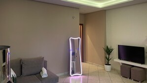Ein modernes Wohnzimmer mit einer Couch, einem Fernseher, einem Spiegel und einer Zimmerpflanze.