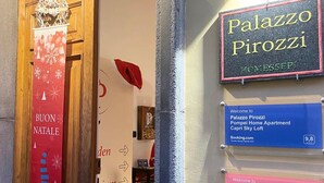 Ein Hotel Eingang mit einem Schild für 'Palazzo Pirozzi' und einer 'BUON NATALE'-Dekoration.