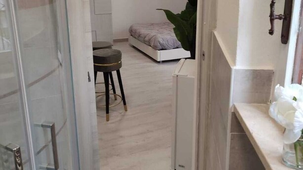 Ein modernes Schlafzimmer mit einem Bett, einem kleinen Tisch und einer Topfpflanze.
