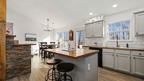 Una cocina con una isla central, taburetes de bar y un comedor con sillas.