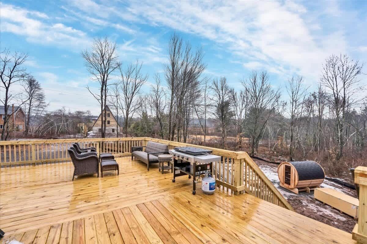 Eine Holzterrasse mit Gartenmöbeln, einem Grill und einer Sauna.
