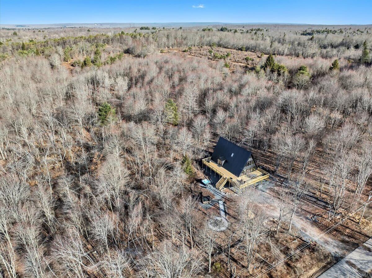 Vue aérienne d’un chalet isolé, entouré d’une végétation clairsemée et desséchée.