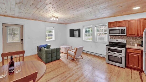 A kitchen with wooden cabinets, a microwave, an oven, and a dining area with a table and chairs.
