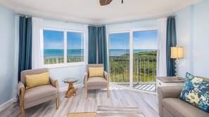 A room with two armchairs, a small table, and a sofa, all facing large windows with a view of the ocean. - Ocean View Treehouse | 2 Kings | Ocean Pointe 3403 (Tavernier)