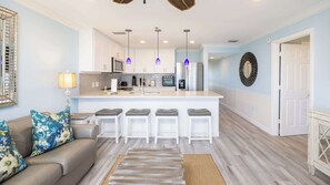 A modern kitchen with white cabinets, a central island with bar stools, and pendant lighting. - Ocean View Treehouse | 2 Kings | Ocean Pointe 3403 (Tavernier)