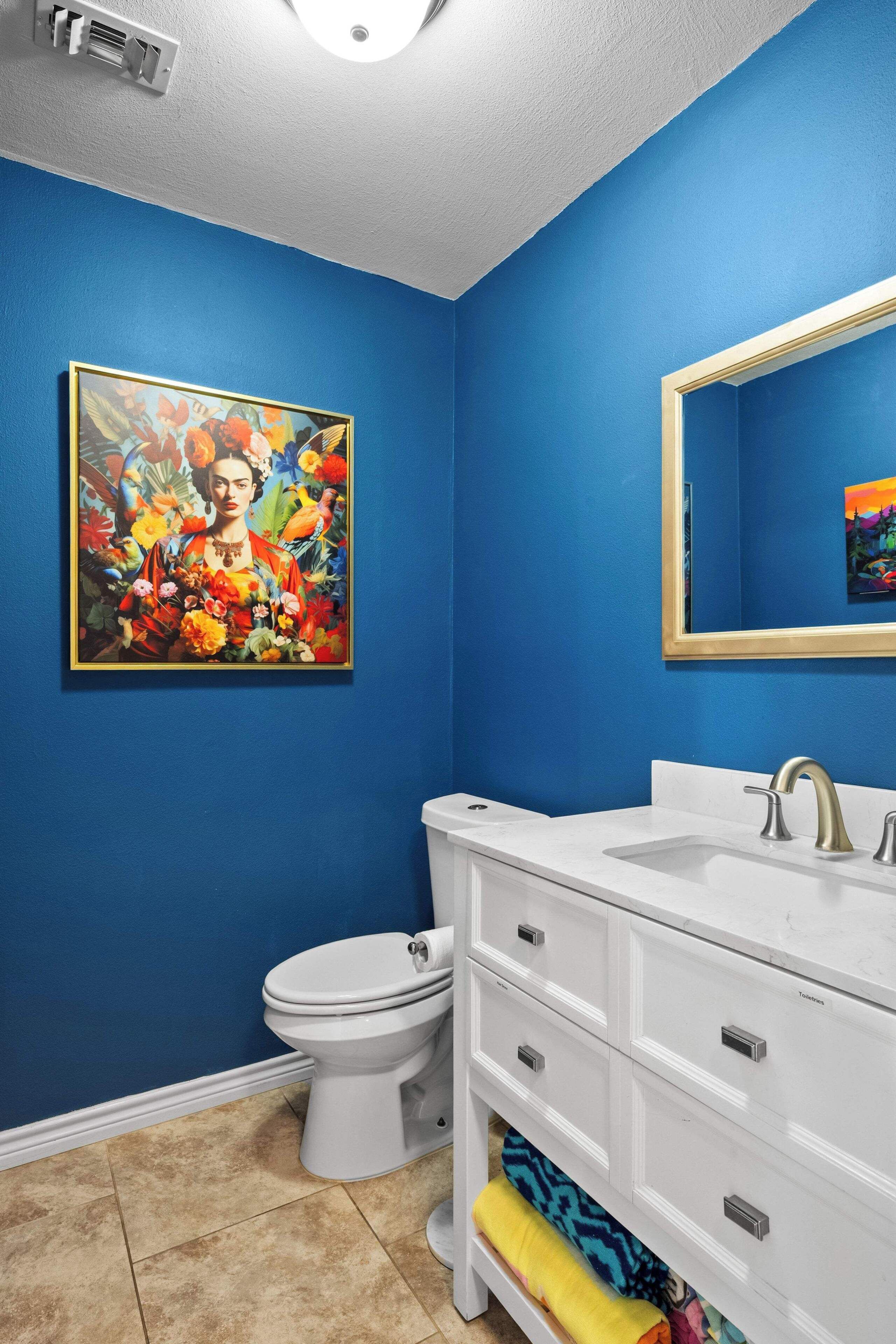 A bathroom with blue walls, a white sink, and a toilet.
