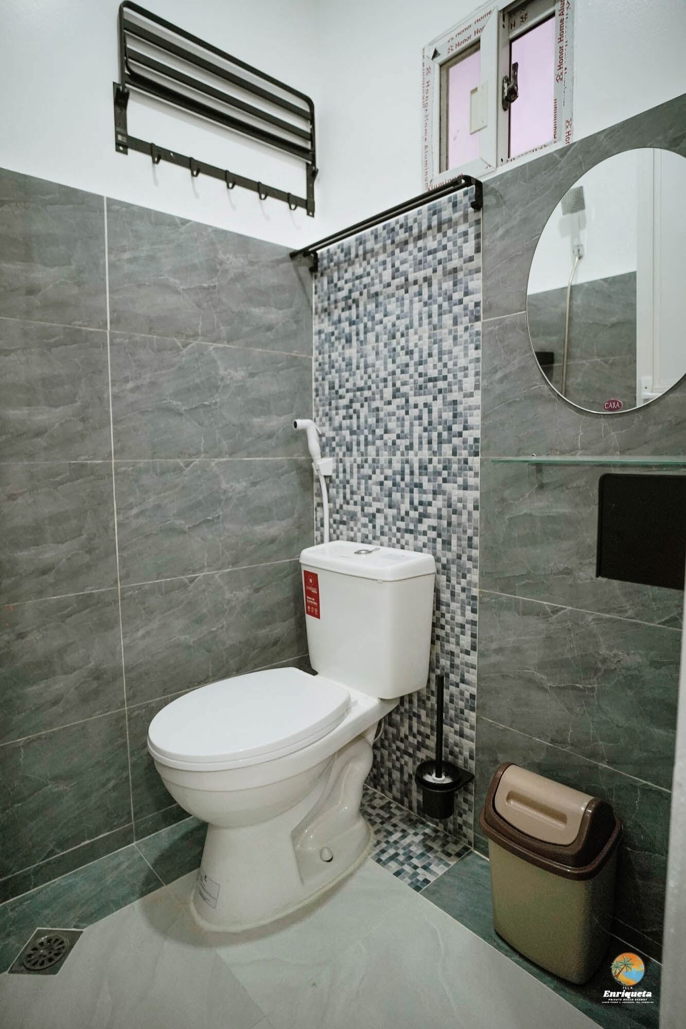 Une salle de bain comprenant des toilettes, un bidet, une poubelle, un porte-serviettes et un miroir.